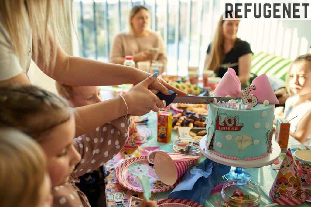 a group of people sitting around a table with a cake